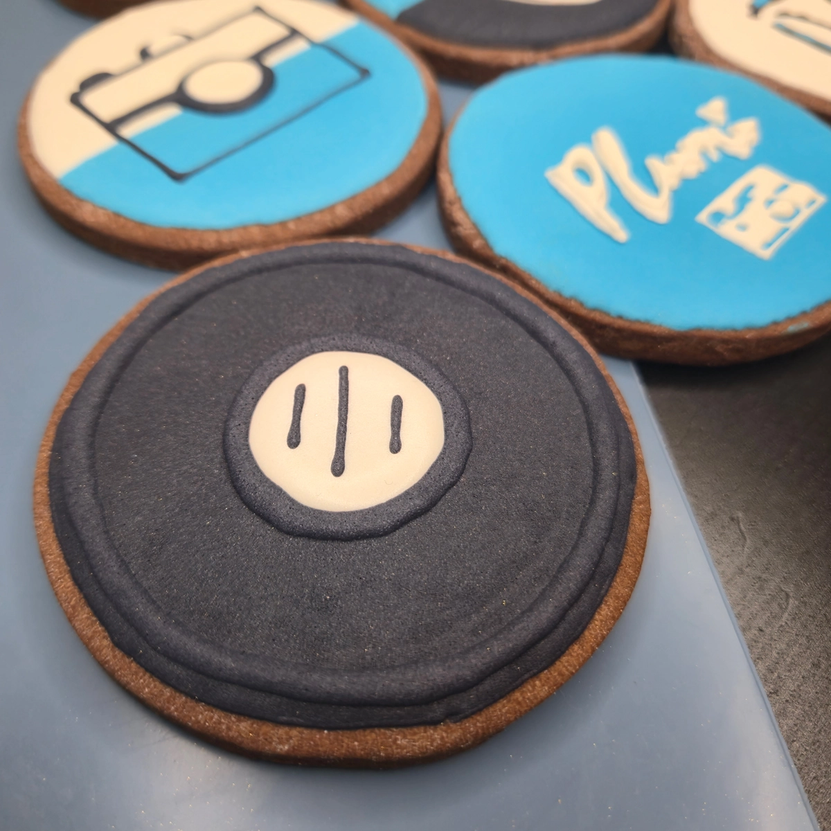 Bolachas de manteiga com cacau decoradas com glacê real com branding da empresa de fotografia Plumi. - Bolos de aniversário no Porto | Bento Cakes, Cake Design, Bolachas e Cupcakes | Porto | Sahri Dessert Art